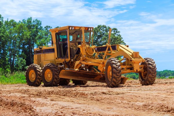 An earthmoving construction grader tractor at construction site