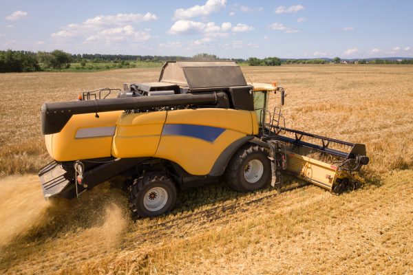 Aerial view of combine harvester harvesting large ripe wheat field. Agriculture from drone view.